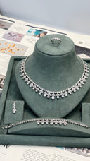 Aviola CZ bridal jewelry set with rhodium-plated necklace, bracelet, earrings and ring on a green display