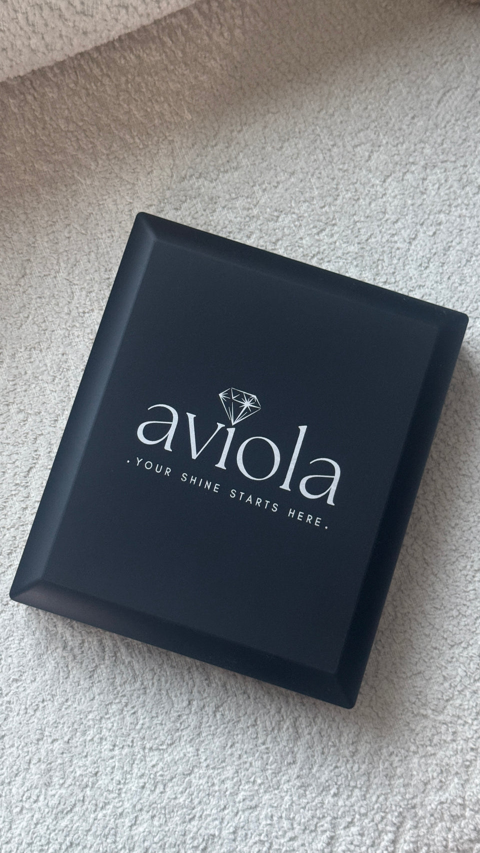 Black jewelry box with 'aviola' logo on a textured surface