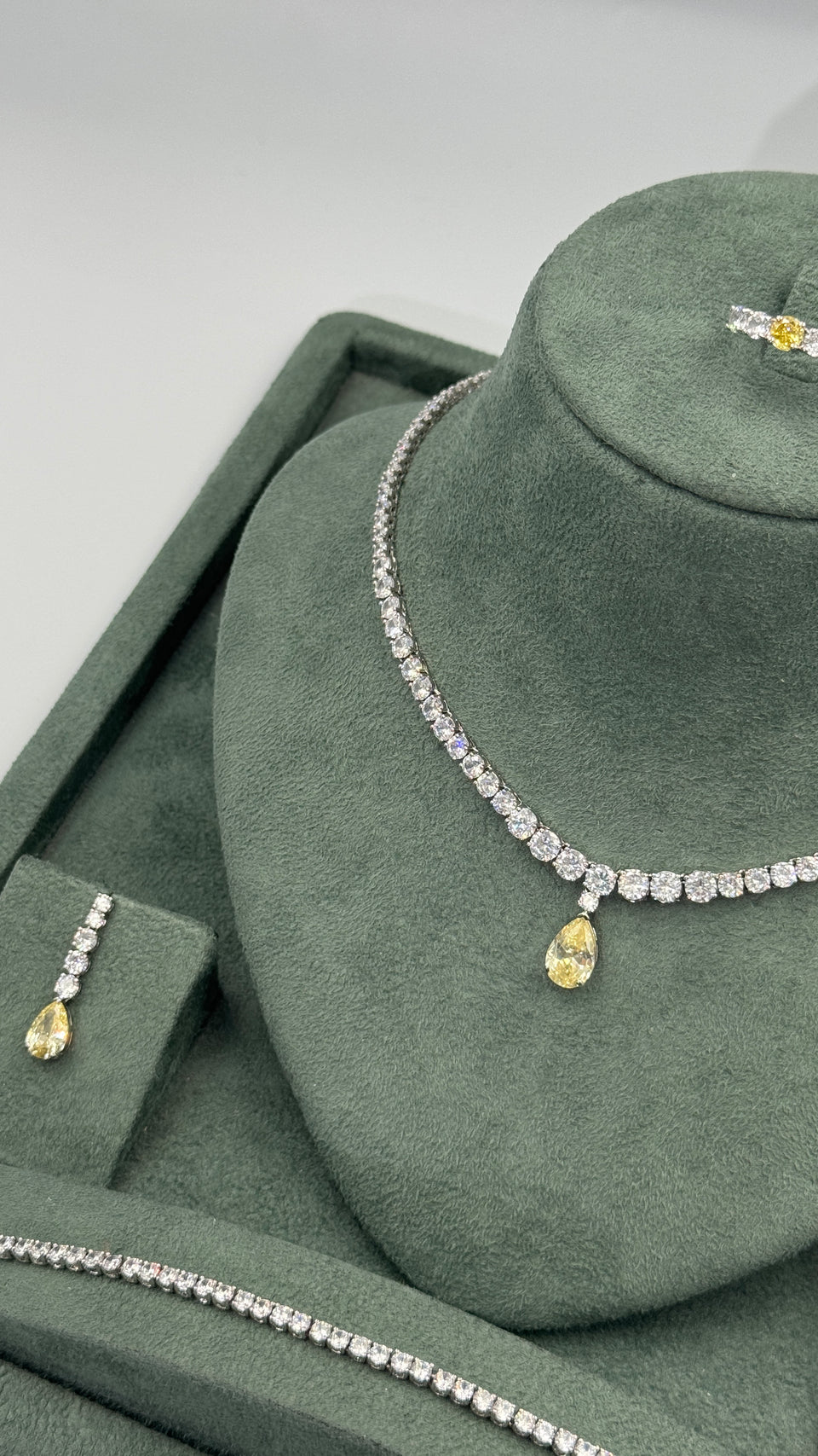 Graduated round-cut zircon tennis bracelet worn on the wrist with the matching yellow bridal necklace behind