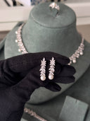 Bridal drop earrings with pearl ends and zircon leaf design held in gloved hand