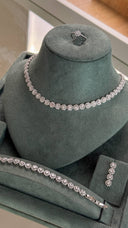 Bridal wedding jewelry set with round cluster necklace, matching bracelet, drop earrings and zircon ring displayed on stand