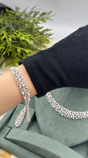 Pearl and marquise leaf bridal statement bracelet worn on the wrist with the matching necklace and earring behind