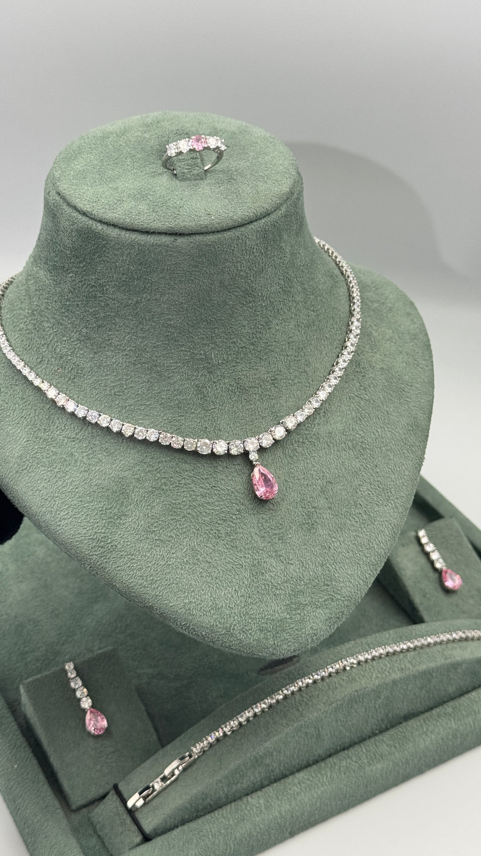 Pink teardrop bridal tennis jewelry set displayed with necklace earrings bracelet and ring