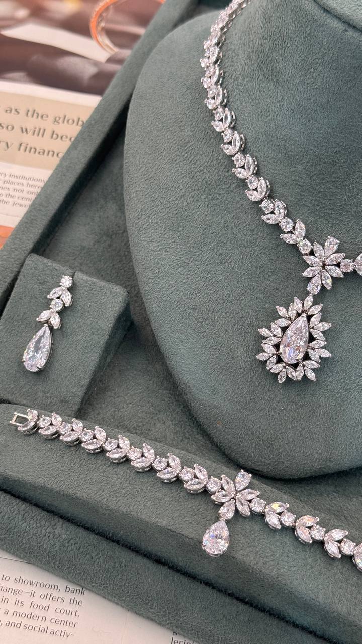 Close view of a floral leaf zircon bridal necklace with a halo teardrop pendant, matching earring and bracelet