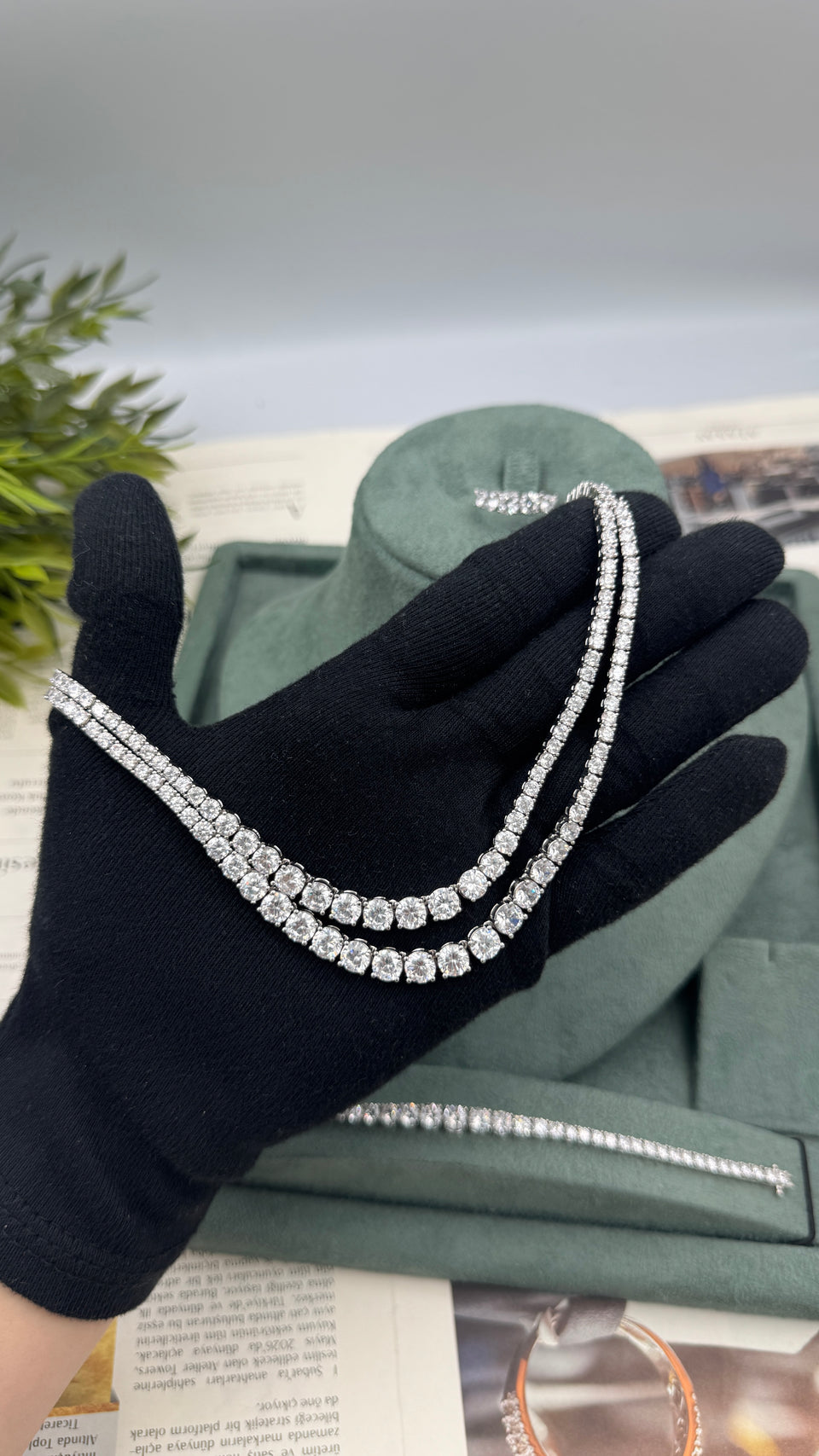 Double-row graduated zircon tennis necklace held by hand to show its flexible layered bridal design