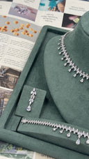 Close view of one marquise leaf bridal earring beside the matching pear-drop fringe necklace and bracelet
