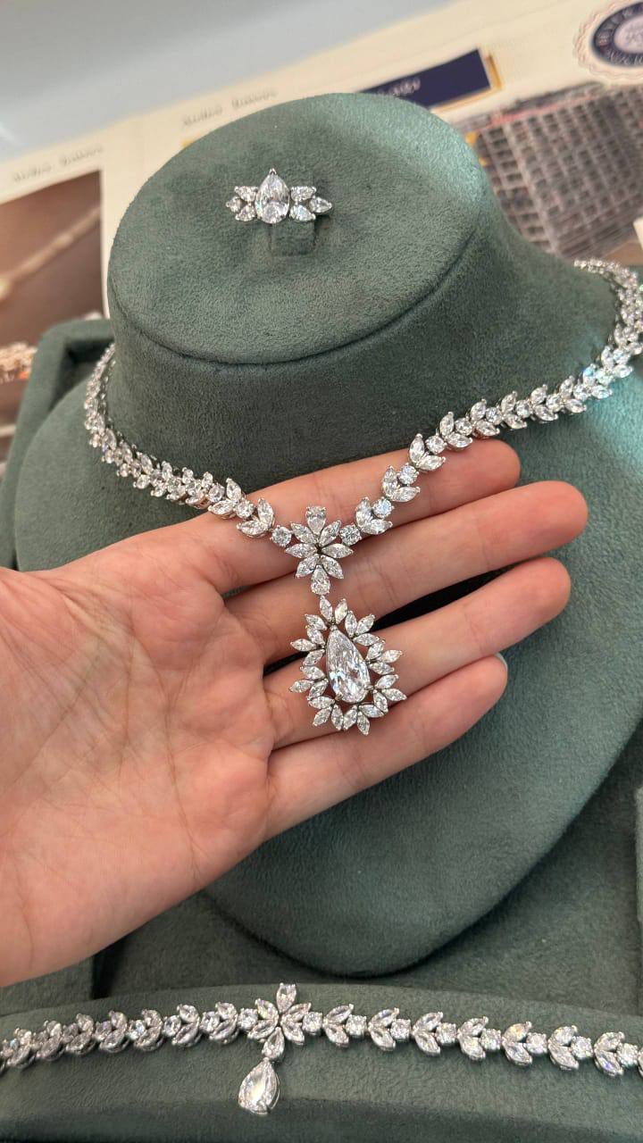 Floral marquise leaf bridal necklace held by hand to show the large pear-cut halo pendant and intricate zircon details