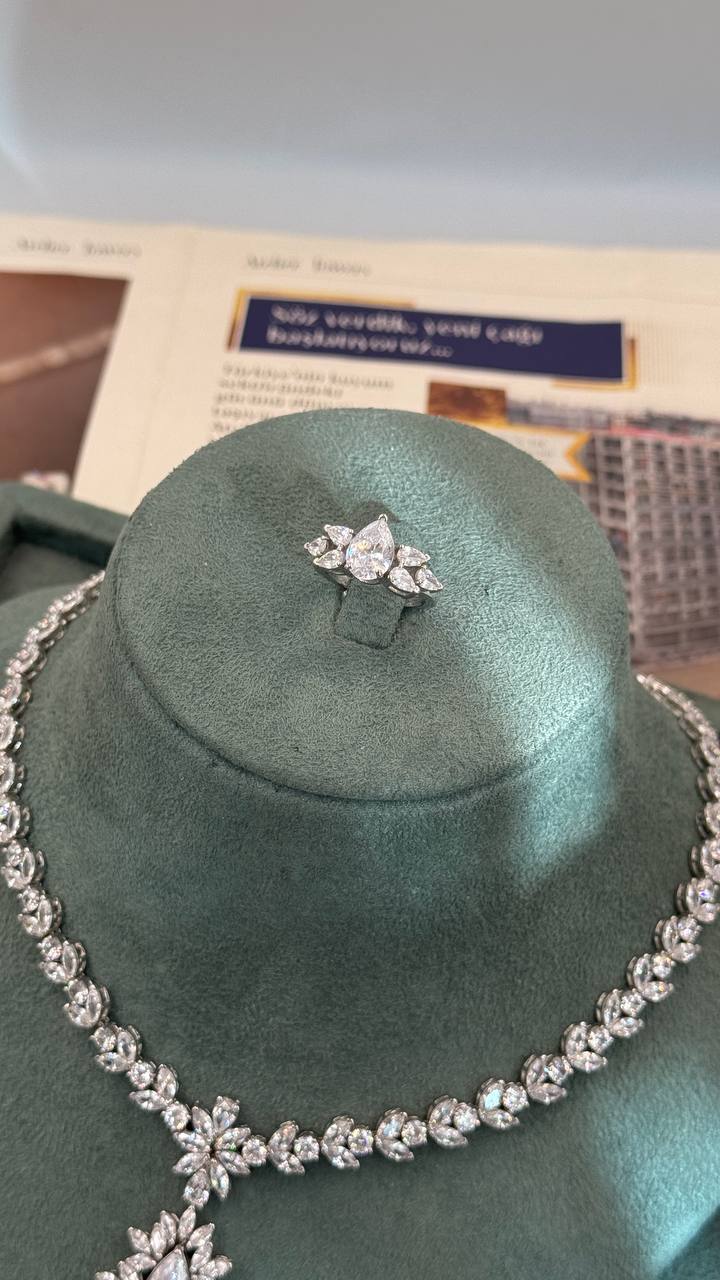 Adjustable silver bridal ring with a pear-cut zircon center and leaf-shaped side stones above the matching necklace