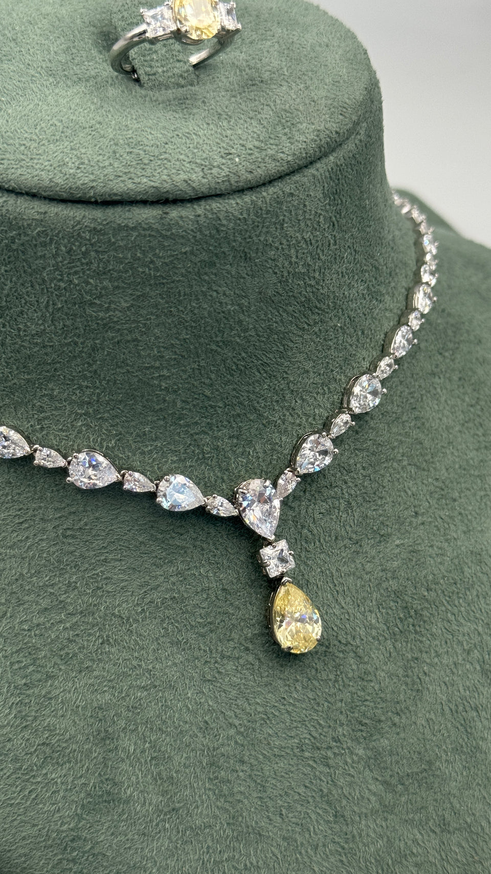 Close-up of a graduated pear-cut tennis bridal necklace with a princess-cut accent and yellow teardrop pendant