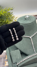 Pair of teardrop zircon bridal earrings held beside a matching Y necklace, two bracelets and adjustable ring wedding jewelry set