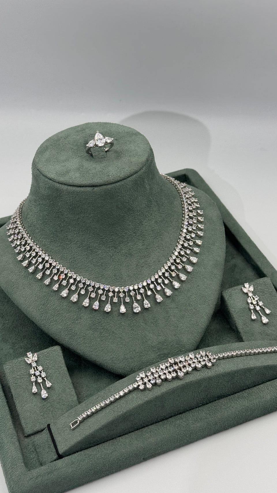 Complete four piece bridal jewelry set with statement teardrop fringe necklace chandelier earrings bracelet and adjustable ring