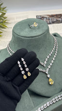 Pair of yellow teardrop bridal earrings held before a matching layered zircon wedding necklace and adjustable ring