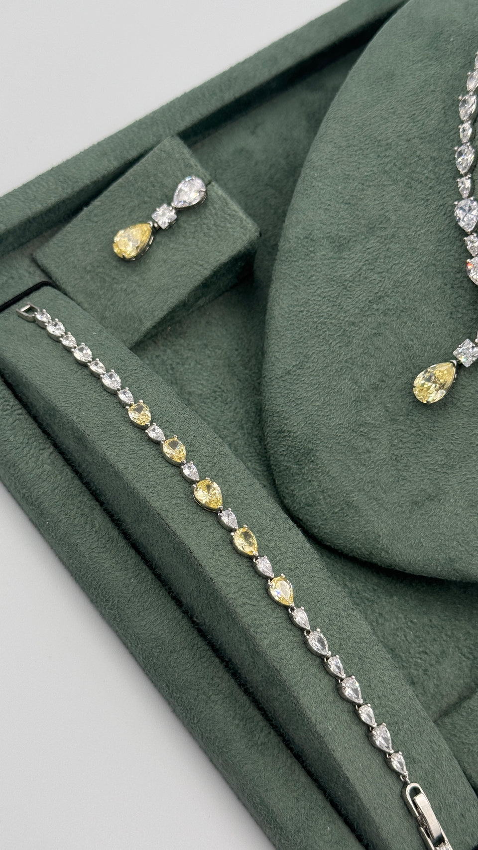 Two-tone bridal tennis bracelet with clear and yellow pear-cut zircon stones beside the matching necklace and earring