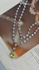 Close-up of a layered pear-cut zircon bridal necklace with a large golden-yellow teardrop wedding pendant
