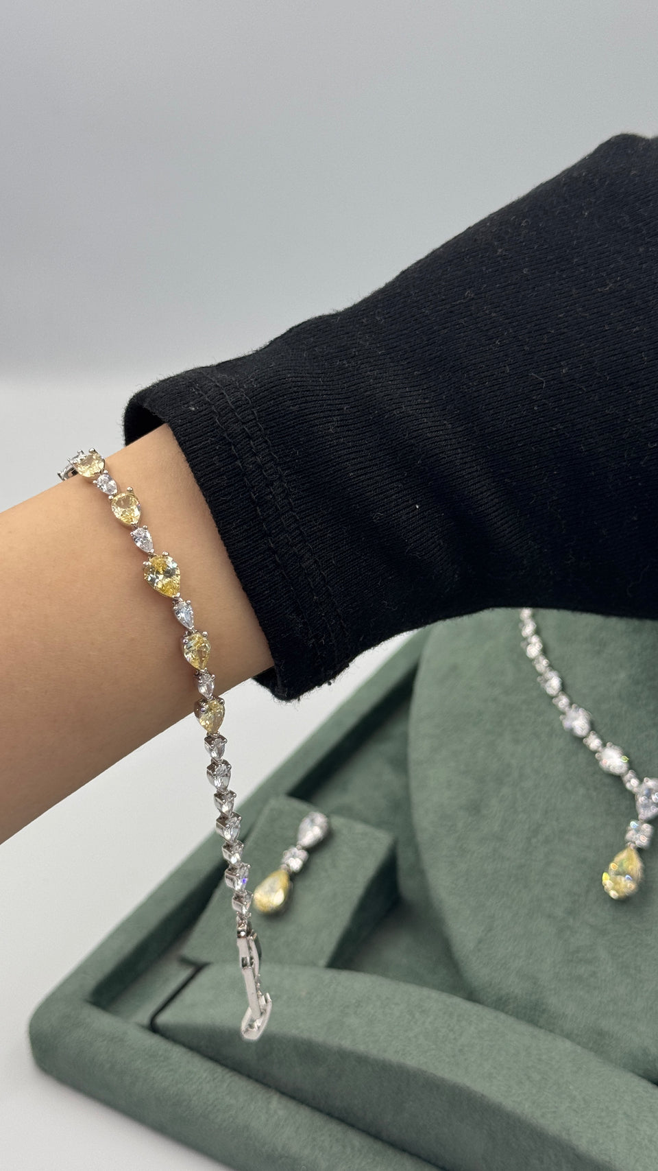 Clear and yellow pear-cut zircon tennis bracelet worn on the wrist with the matching bridal necklace behind