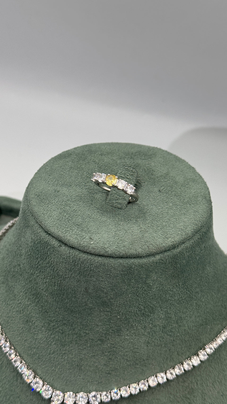 Close-up of an adjustable bridal ring with a yellow center stone and clear round zircon side stones