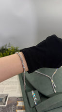 Clear zircon tennis bracelet worn on the wrist with a matching double-drop Y necklace and earrings behind
