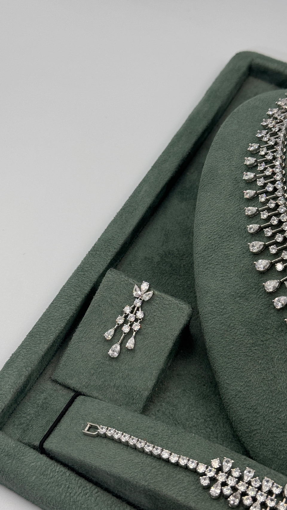 Chandelier drop earring and matching teardrop fringe tennis bracelet displayed beside the bridal necklace