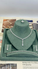Jewelry set including necklace, earrings, and ring on a green stand with a newspaper background.