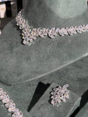 Silver necklace and earrings on a green stand