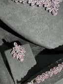 Close-up of a diamond earring on a green cushion with a blurred background