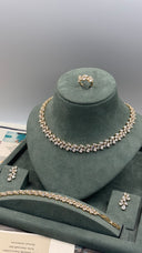 A gold-tone jewelry set displayed on a dark green velvet mannequin bust, including a necklace, matching bracelet, ring, and earrings, with a matching tray in front.