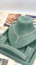 Jewelry set including necklace, earrings, and ring on a green velvet stand with newspaper background