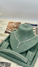 Silver necklace on a green mannequin bust with newspaper in the background