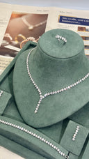 Jewelry set including necklace, earrings, and ring on a green velvet stand with newspaper background