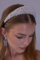 Pearl bridal tiara worn by a bride, featuring white pearls and clear faceted beads in a wide luxury wedding crown design