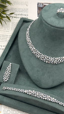 Close display of a luxury pearl bridal necklace with marquise zircon leaves, one matching drop earring, bracelet and adjustable ring