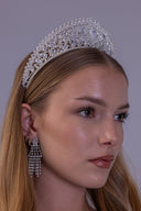 Royal silver zircon bridal crown worn by a bride, featuring ornate scrollwork and a central teardrop stone for a luxury wedding look.