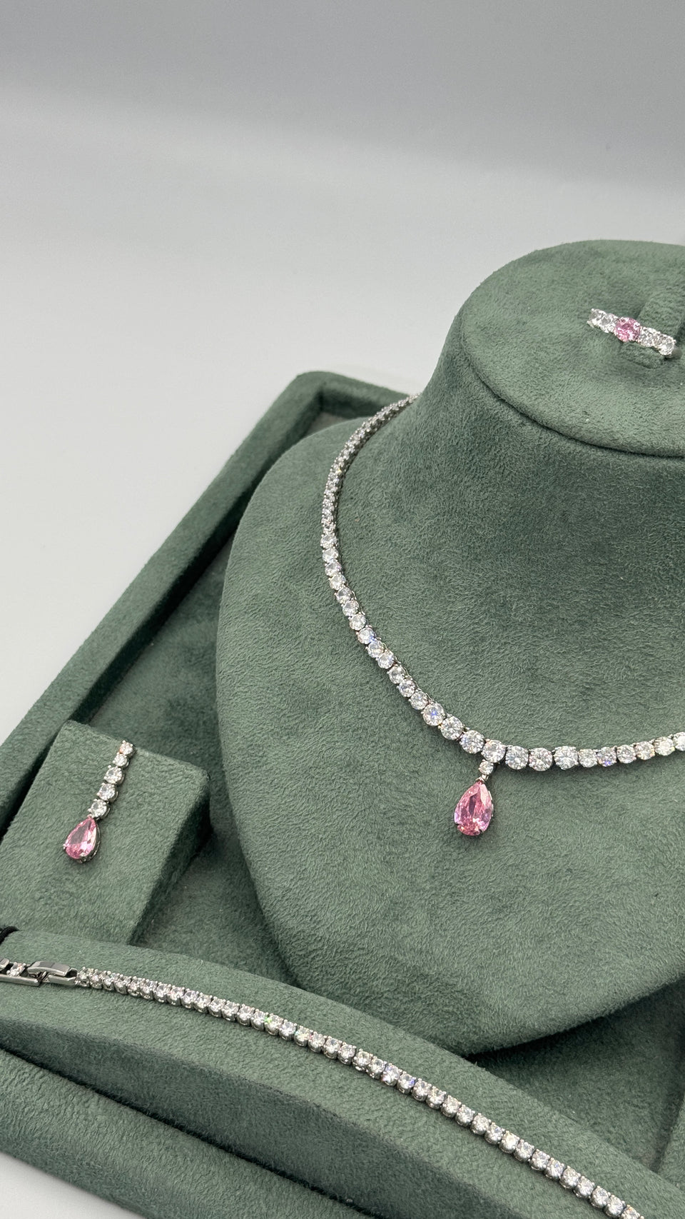 Close view of clear round zircon Riviera necklace with graduated stones and pink pear cut teardrop pendant