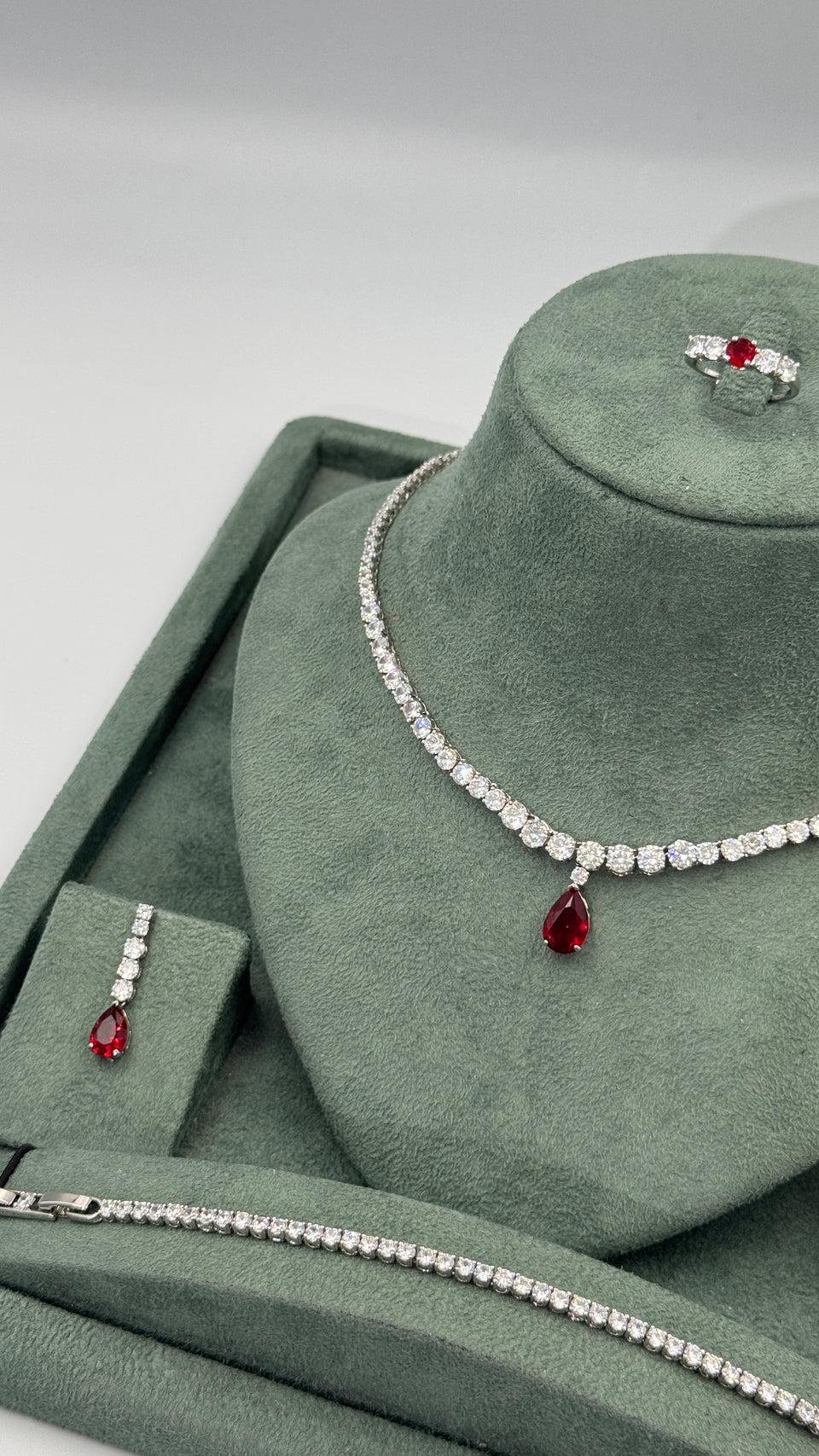 Close view of clear round zircon Riviera necklace with graduated stones and ruby red pear cut pendant