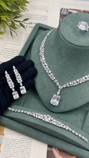 Pair of marquise zircon bridal drop earrings with rectangular emerald-cut stones held beside the matching necklace, bracelet and ring