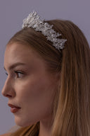 Front close-up of a pearl bridal crown with clear beaded flowers, botanical branches and a graceful wedding tiara silhouette.