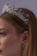 Close-up of a silver celestial wedding crown showing white pearl clusters, clear faceted beads and sparkling five-point star details.