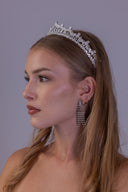 Angled bridal portrait featuring a regal silver zircon tiara with a polished double-arch silhouette and symmetrical crown design.