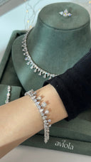 Clear pear cut teardrop fringe tennis bracelet worn on the wrist with a matching bridal necklace behind