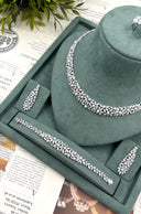 Detailed wedding jewelry display showing a pearl botanical necklace, two matching earrings, bracelet and partial ring
