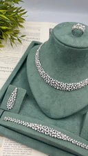 Pearl and zircon wedding jewelry set displayed with a botanical necklace, one floral earring, matching bracelet and cluster ring